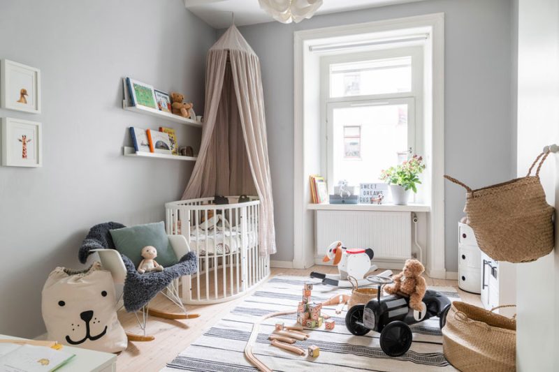 Voor deze babykamer is er gekozen voor een neutraal kleurenpalet met lichtgrijze muren en een mooie houten vloer.