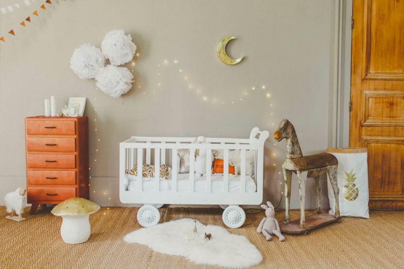 In deze super leuke babykamer, ontworpen door Estelle Williot, met een geweldig mooi kleurenpalet is slingerverlichting boven het bedje opgehangen aan de muur.