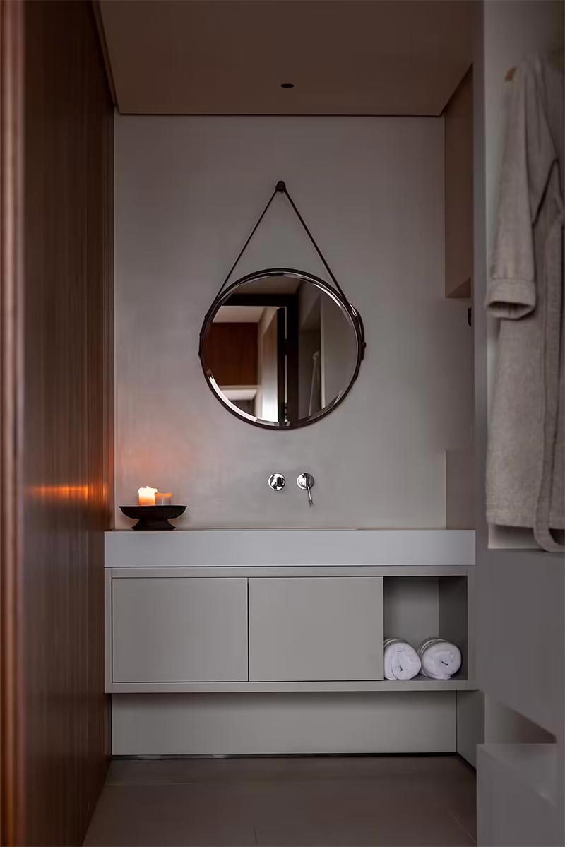 Dezelfde stijl is doorgetrokken naar de luxe badkamer, met een tijdloze combinatie van betonstuc en hout.