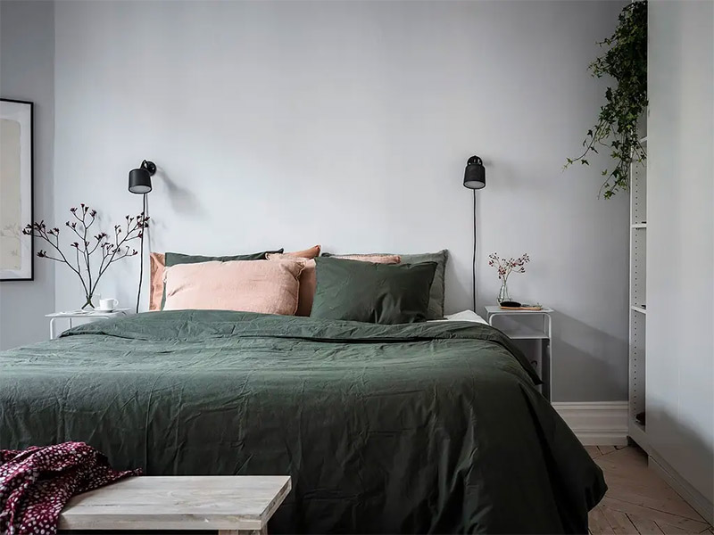 Een vleugje groen kan nooit kwaad in de slaapkamer. Het groene beddengoed staat super mooi bij de grijze muur in deze slaapkamer.