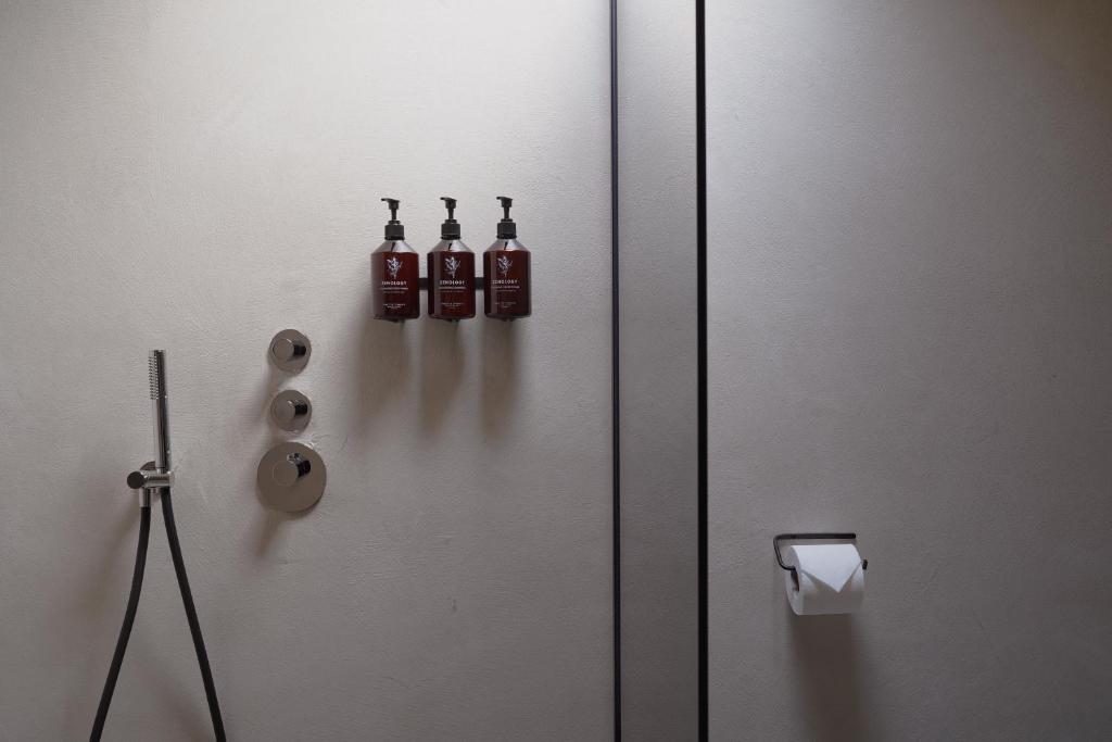 Dit is de super mooie badkamer van Hotel âme in Rotterdam, waar een flessenhouder met Zenology flessen aan de muur is gemonteerd in de douche.