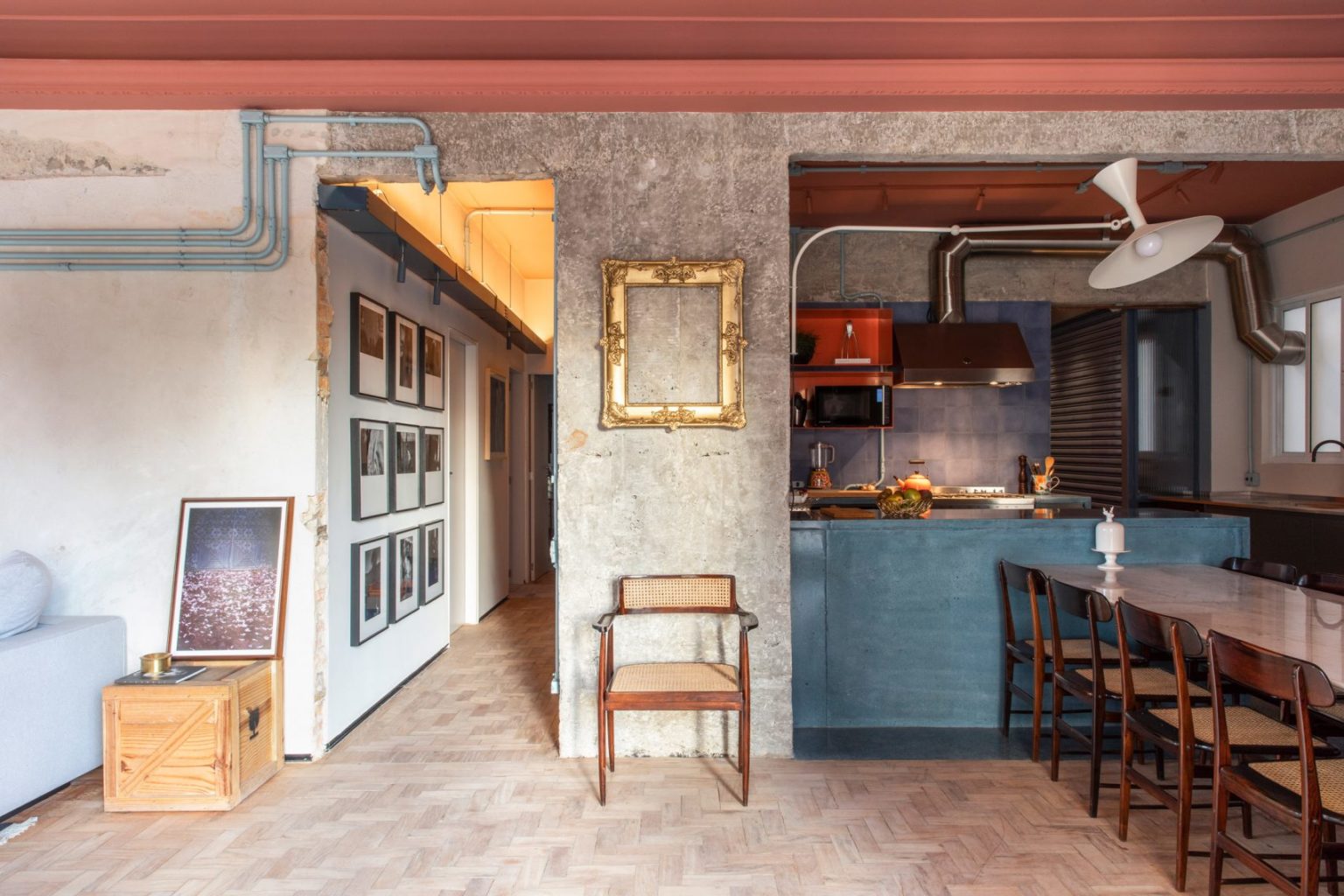 In dit stoere appartement uit São Paulo is een eclectische keuken ontworpen met een schiereiland waar een grote eettafel aan gemonteerd is.