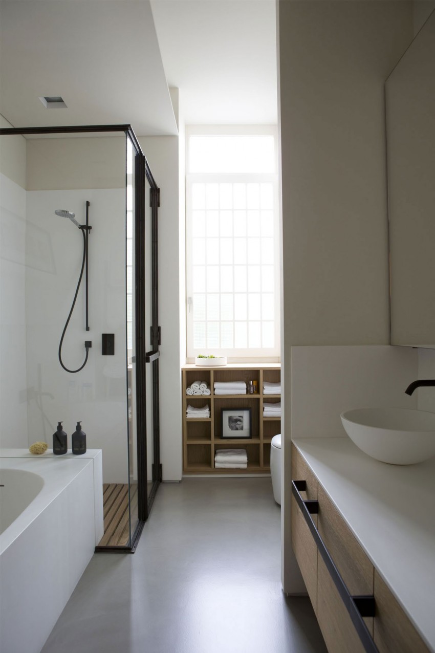 De lichte gietvloer in deze moderne badkamer vormt een perfecte combinatie met de houten onderdelen en het zwarte industriële staal - ontworpen door ontwerper Fabio Fantolino.