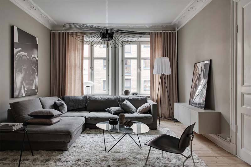 In deze mooie Scandinavische woonkamer vind je verschillende designklassiekers, waaronder de Petite Friture Vertigo hanglamp en de Gubi Pedrera salontafel met zwart onderstel.