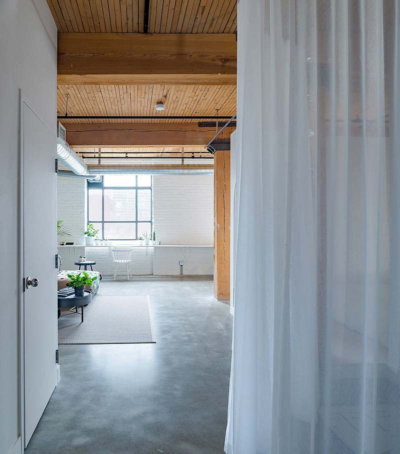 In het Broadview loft appartement is er gekozen voor een stoere betonlook gietvloer, gecombineerd met wit geverfde bakstenen muren en warm houten plafond.