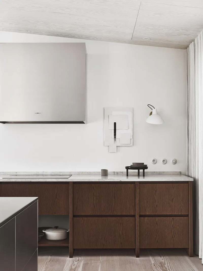 Hier zie je de prachtige houten keuken van Nordiska Kök, in het huis van een architect, waar een een marmeren werkblad is gecombineerd met een strak gestuukte witte en gecoate keukenachterwand. 