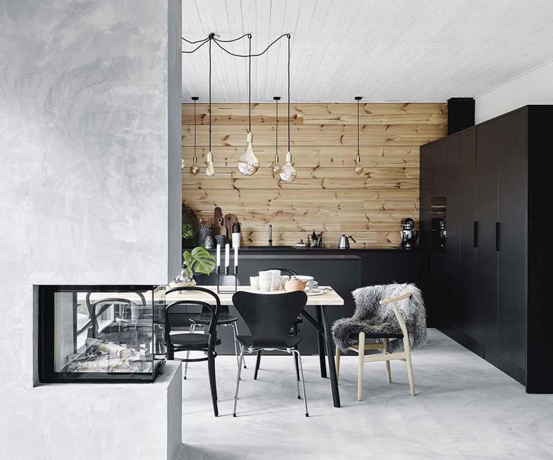 Marjo en Eetu hebben gekozen voor een mooie natuurlijke houten keukenachterwand, die heel veel warmte toevoegt in deze moderne keuken met zwarte kasten en betonlook vloer. 