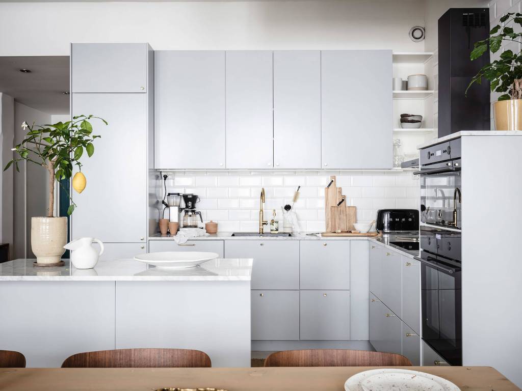 De keukenachterwand van deze mooie keuken is optimaal beschermd met witte metrotegels dei tot de wandkasten lopen. 