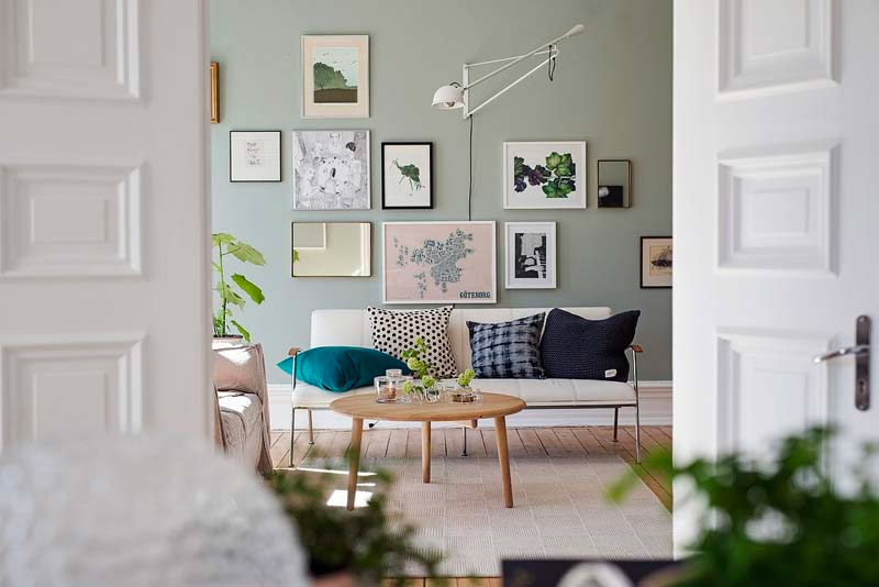 De groene muur met collage met lijsten vormt het focal punt in deze zithoek.