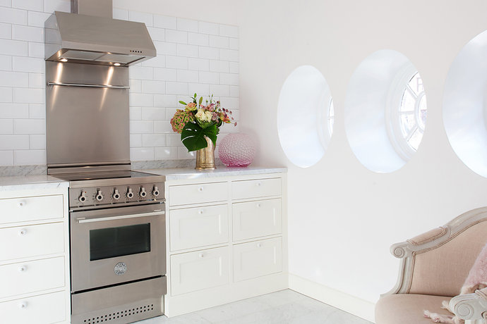 Landelijke keukenstijl met witte keukenkasten, witte metrotegels en ronde ramen