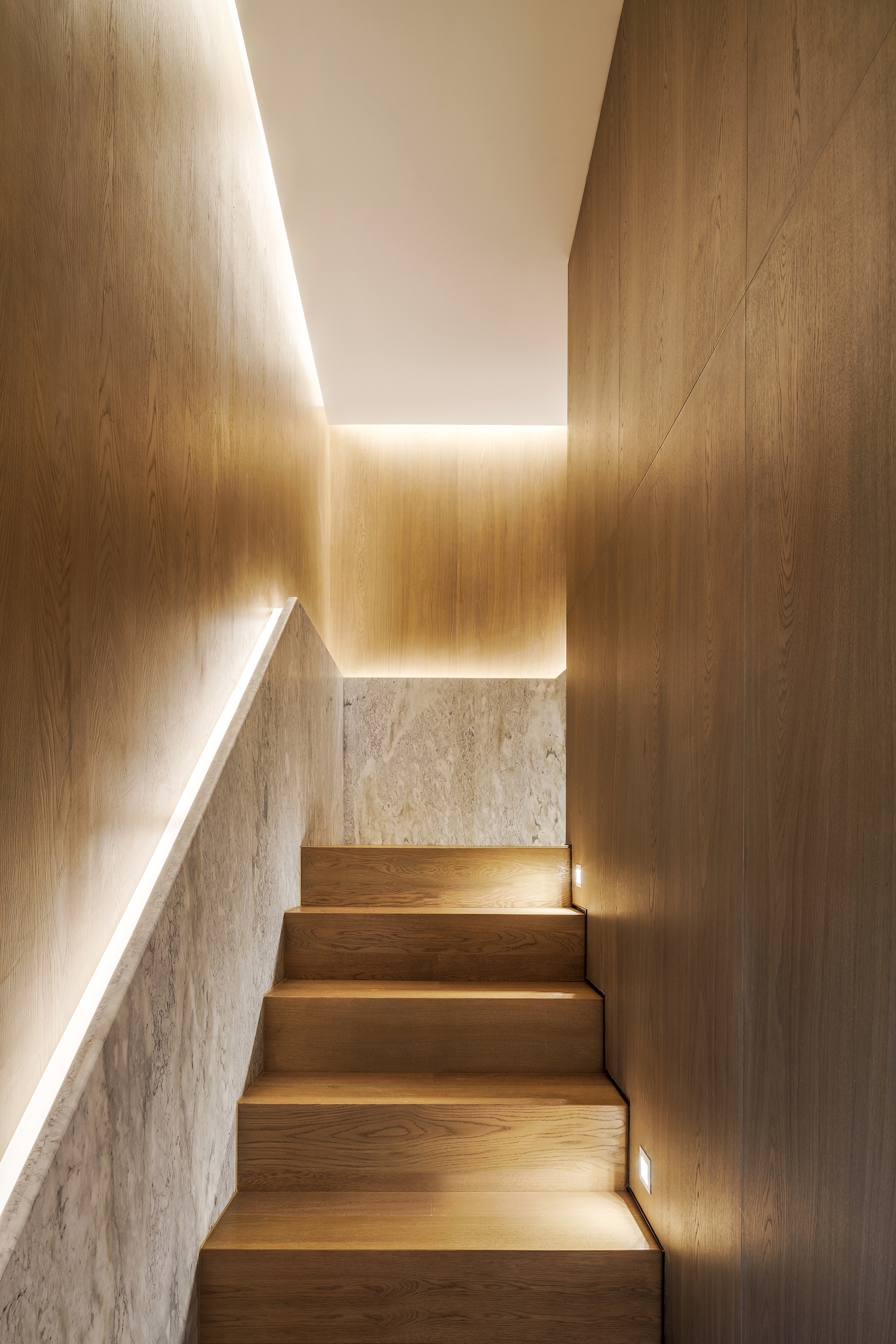 Deze luxe trap, een ontwerp van Mason Studio, combineert strakke inbouwspots in de wanden met ledstrips in de marmeren trapleuning én in het plafond.