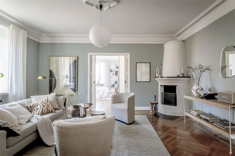 In dit interieur is een mooi balans gecreëerd met mintgroene muren, een houten vloer, en lichte meubels in neutrale kleurtinten.