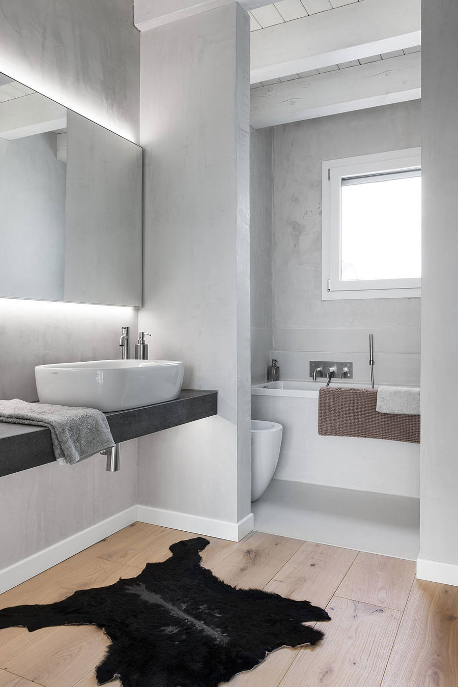 Ook in deze badkamer, ontworpen door Anna Laura Businaro, is er gekozen voor een strakke gietvloer in het natte gedeelte en een houten vloer in het droge gedeelte.