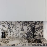 Een strakke witte keuken met een Afyon Violet marmeren achterwand.