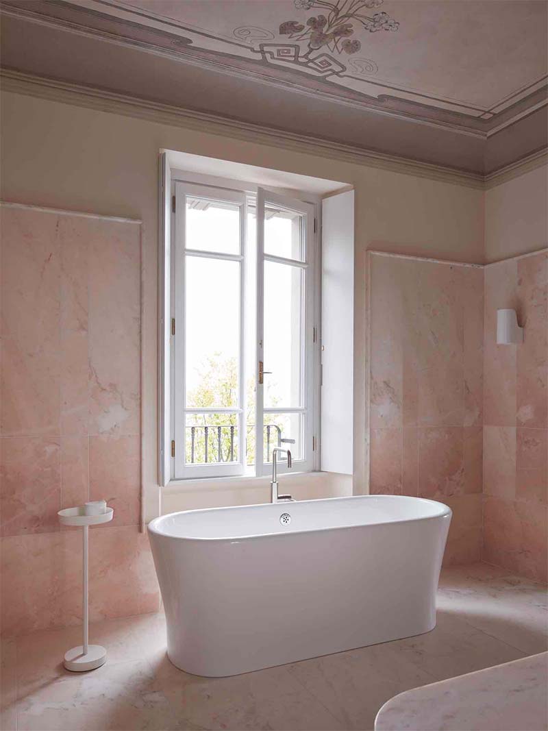 Super mooie roze badkamer met het vrijstaand bad bij het raam.