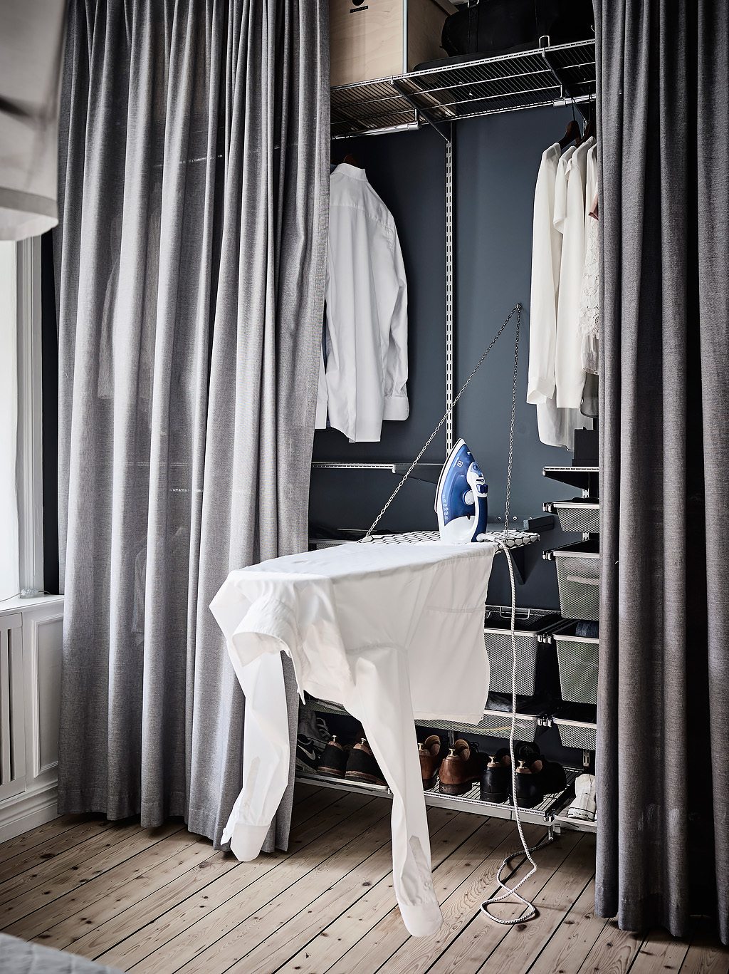 In deze mooie slaapkamer zijn gordijnen opgehangen vóór de open kledingkast