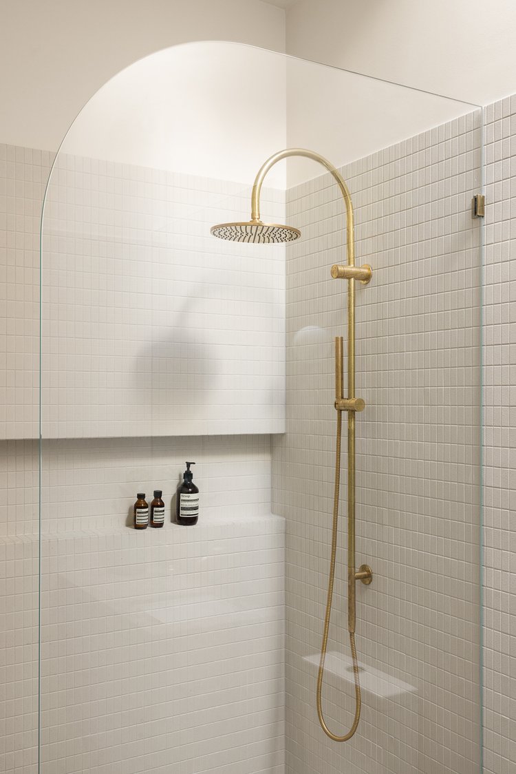 Deze chique badkamer is ontworpen door Homes By Ivy, die een brede nis hebben gecreëerd in de muur van de douche | Fotografie: Dylan James Photography