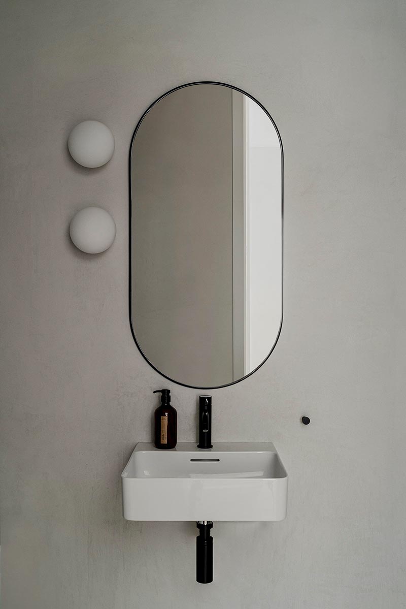 Een grote ovale spiegel boven de compacte wite wastafel in de badkamer.