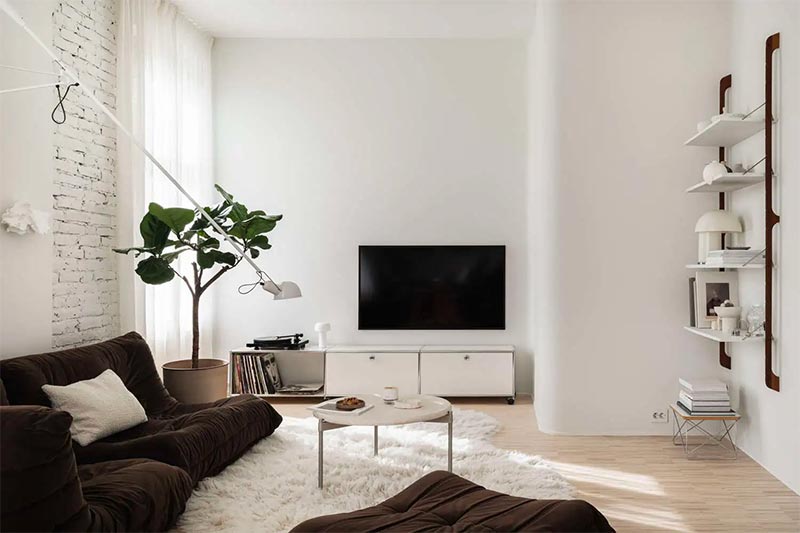 Deze mooie Scandinavische woonkamer is elegant en toch minimalistisch ingericht. De witte muren en het zachte vloerkleed vormen de perfecte achtergrond voor de bruine Togo Ligne Roset bank, die echt opvalt in dit interieur.