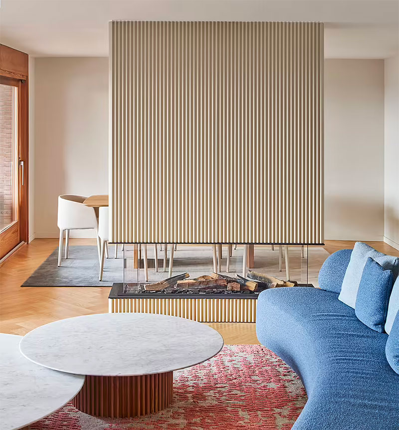 In deze woonkamer, ontworpen door Nomo Studio, wordt de elektrische sfeerhaard gebruikt als een scheidingswand tussen de woonkamer en de eethoek. | Fotografie: José Hevia