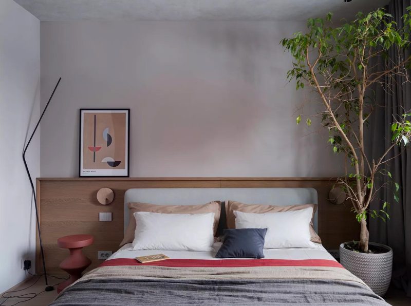 De stijl van de woonkamer is ook doorgevoerd in de slaapkamer, waar het houten hoofdbord op maat prachtig staat bij de kalkverf muur. De kleurrijke accenten komen terug in het bedlinnen, het nachtkastje en de schilderij.