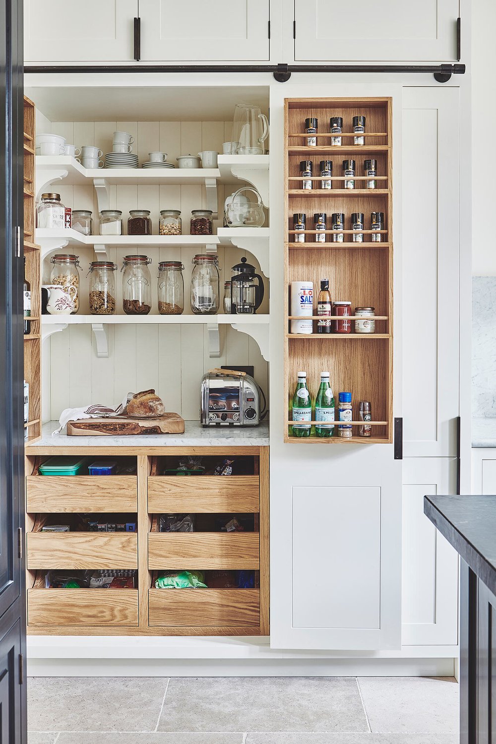 Deze keuken is een ontwerp van Blakes London, met een super mooie op maat gemaakte voorraadkast met van alles erop en eraan. Op de wandplanken vind je zowel kleine glazen voorraadpotten als grote Weckpotten. | Bron: Blakeslondon.com