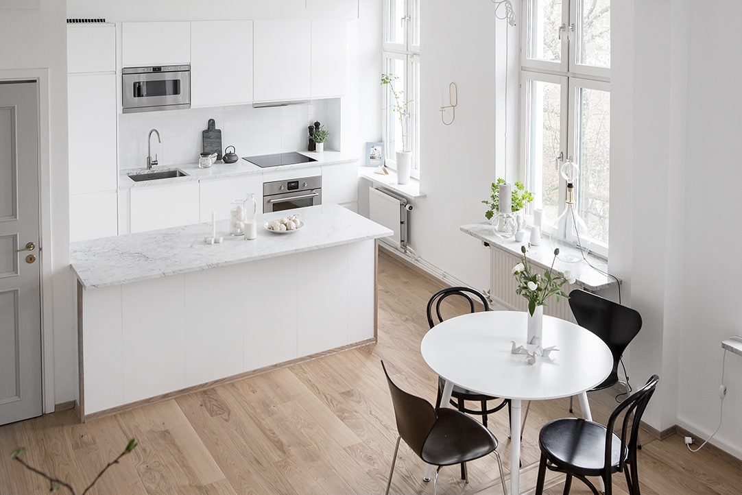 Aan deze ruimtelijke woonkamer is een hele fijne open witte keuken ingericht met een groot schiereiland met marmeren werkblad.